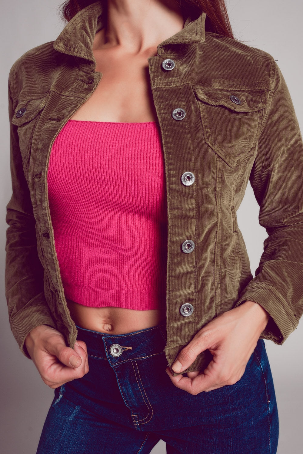 Khaki corduroy jacket with pink crop top and blue jeans.