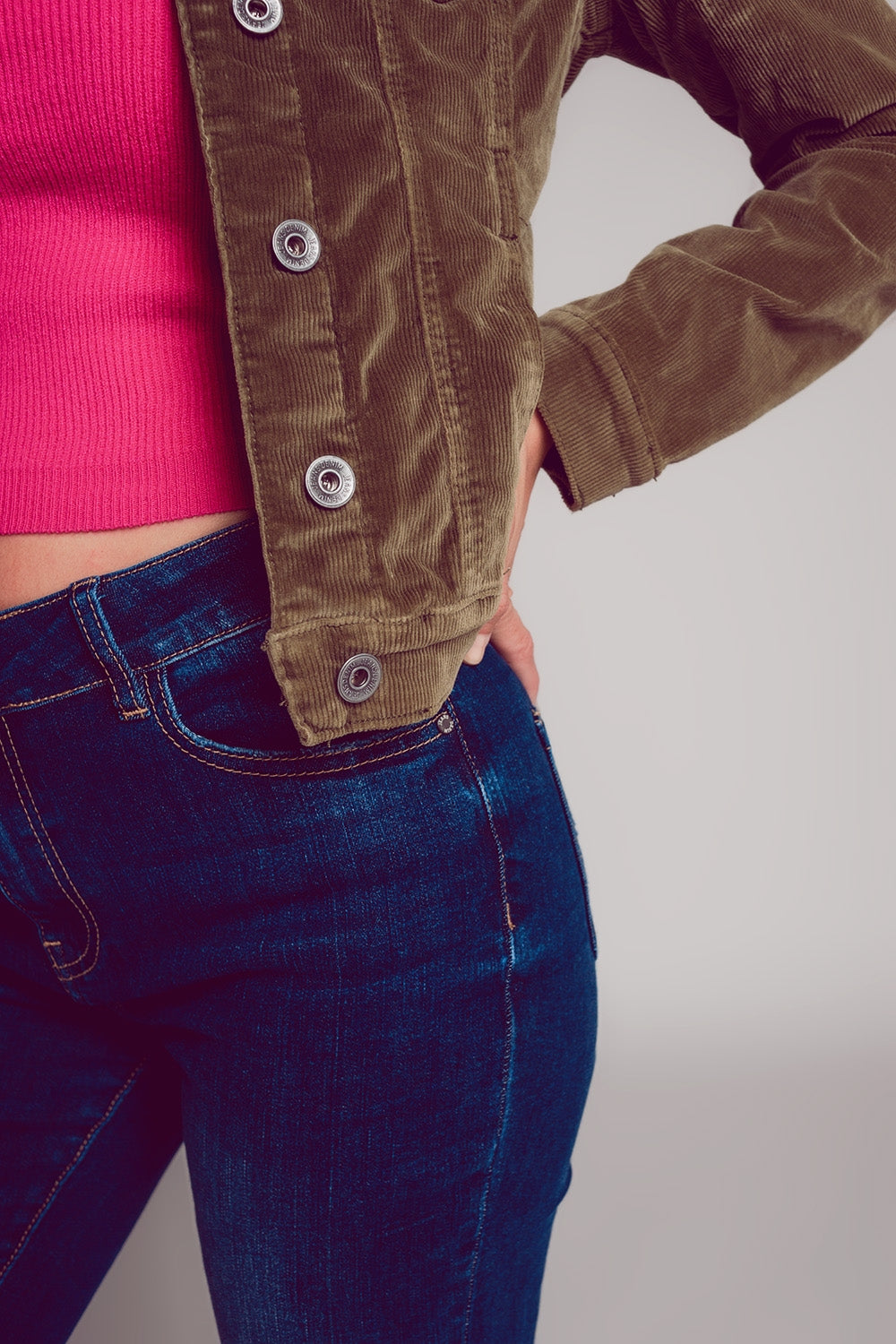 Khaki cropped cord jacket with pink top and dark wash jeans.